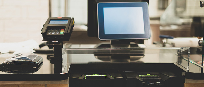 Conjunto de equipamentos que compõem uma estação de self checkout, incluindo tela, leitor e impressora.